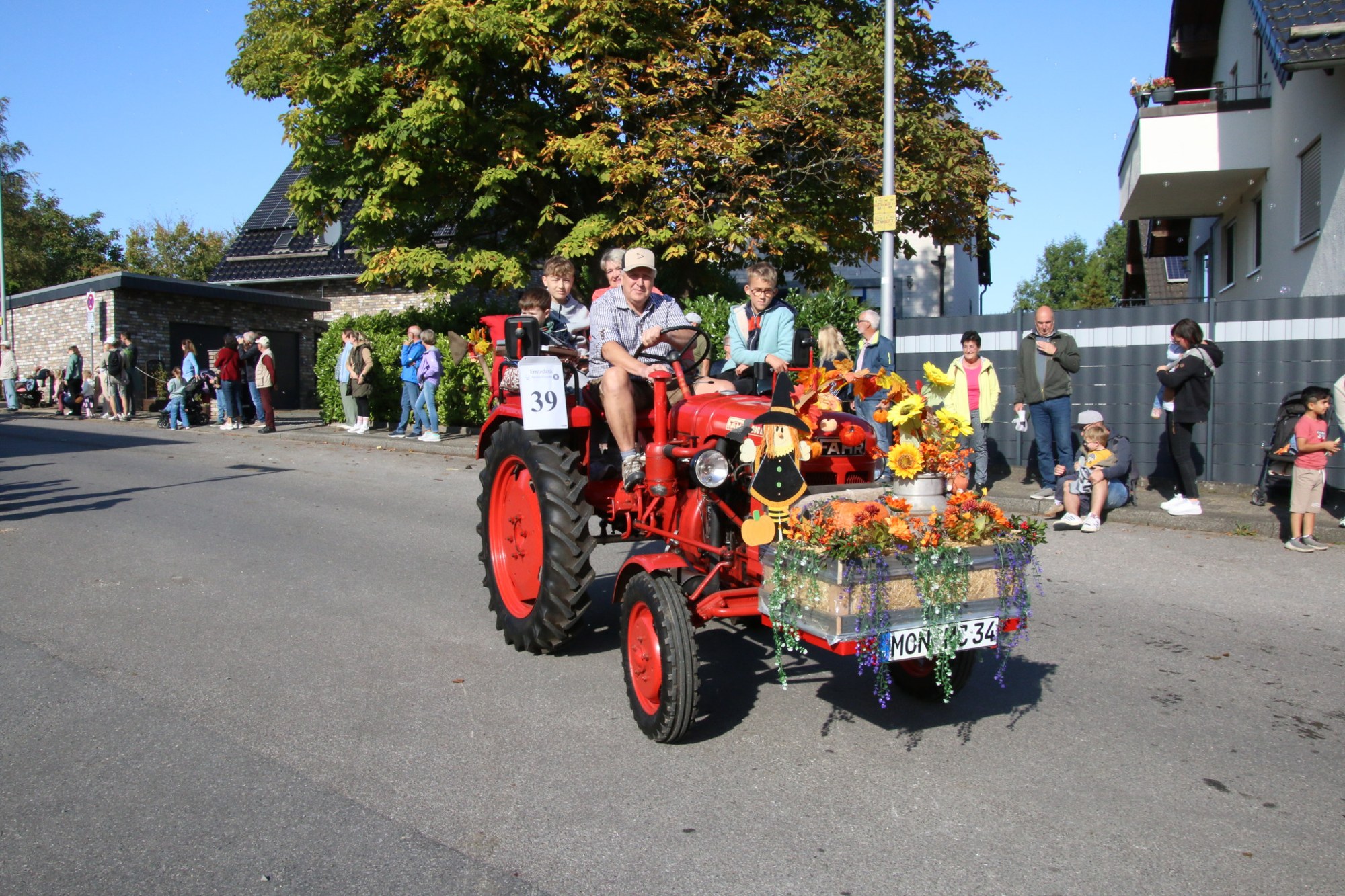 Roter Traktor mit blumengeschmückter Ladefläche beim Erntedankzug Walheim 2026.