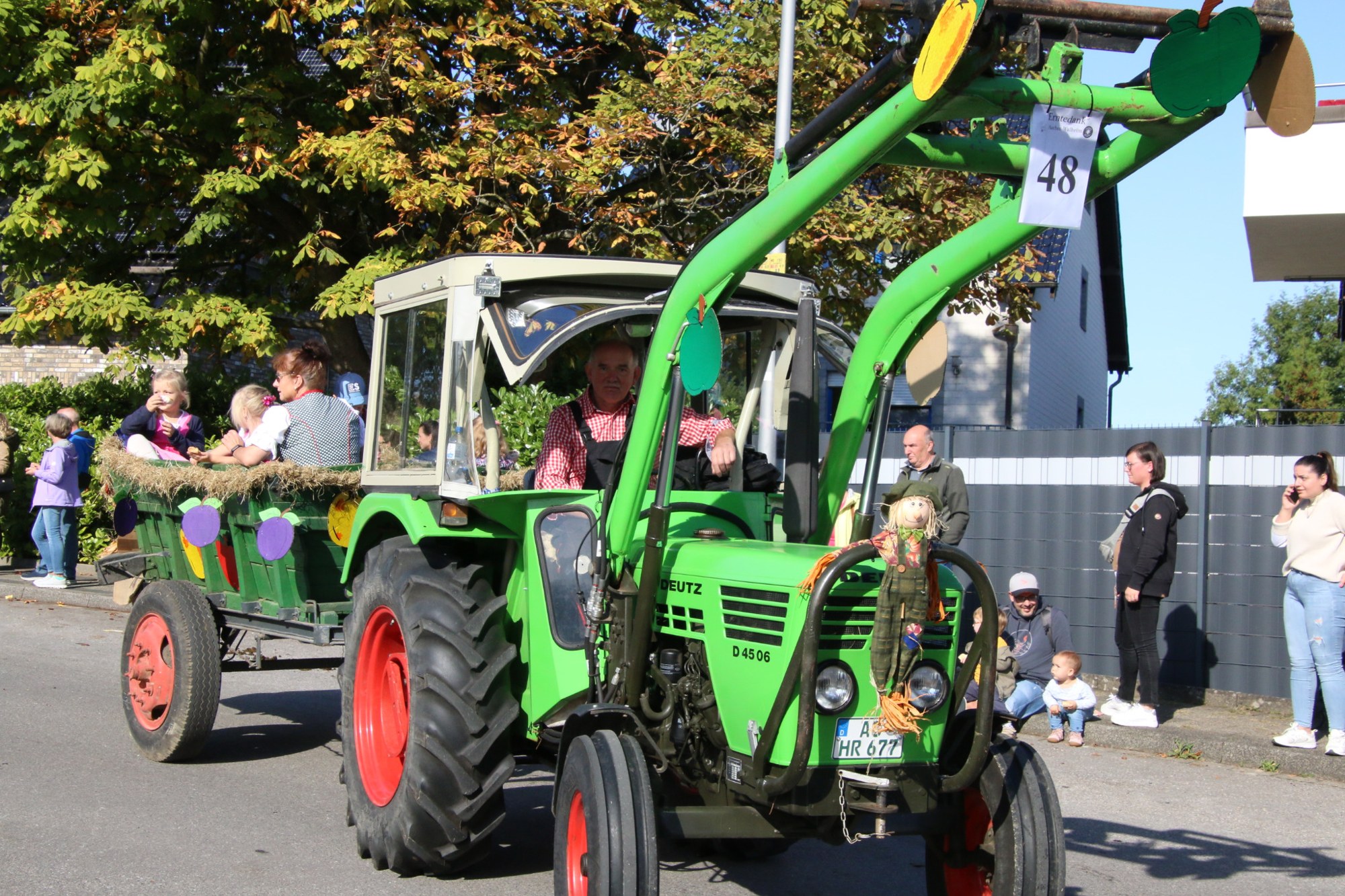 Grüner Traktor mit erhobenem Frontlader beim Erntedankzug Walheim 2026.